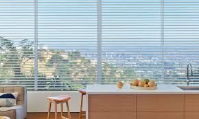 A kitchen with a view of a city and a large window with blinds.