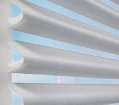 A close up of a white blind with blue stripes on a window.