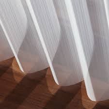 A close up of a white curtain on a wooden floor.