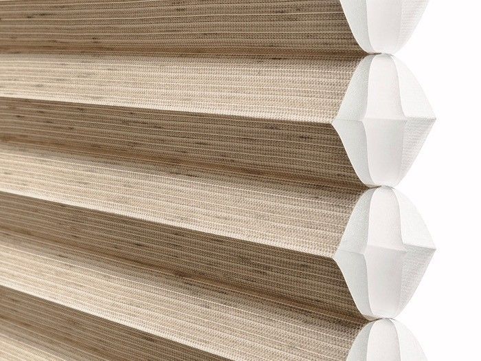 A close up of a honeycomb blind on a white background.