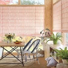 A dining room with a table and chairs and pink roman shades.