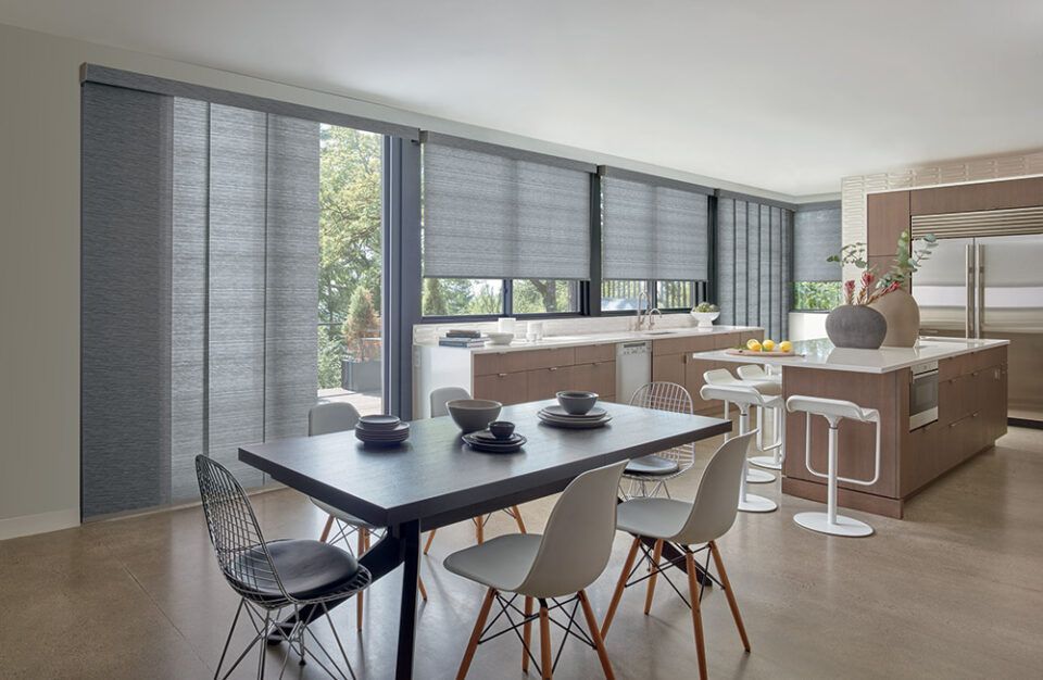 A dining room with a table and chairs and a kitchen.