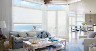 A living room with a couch , table , chairs and a view of the ocean.