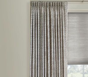 A pair of curtains hanging on a window next to a window with blinds.