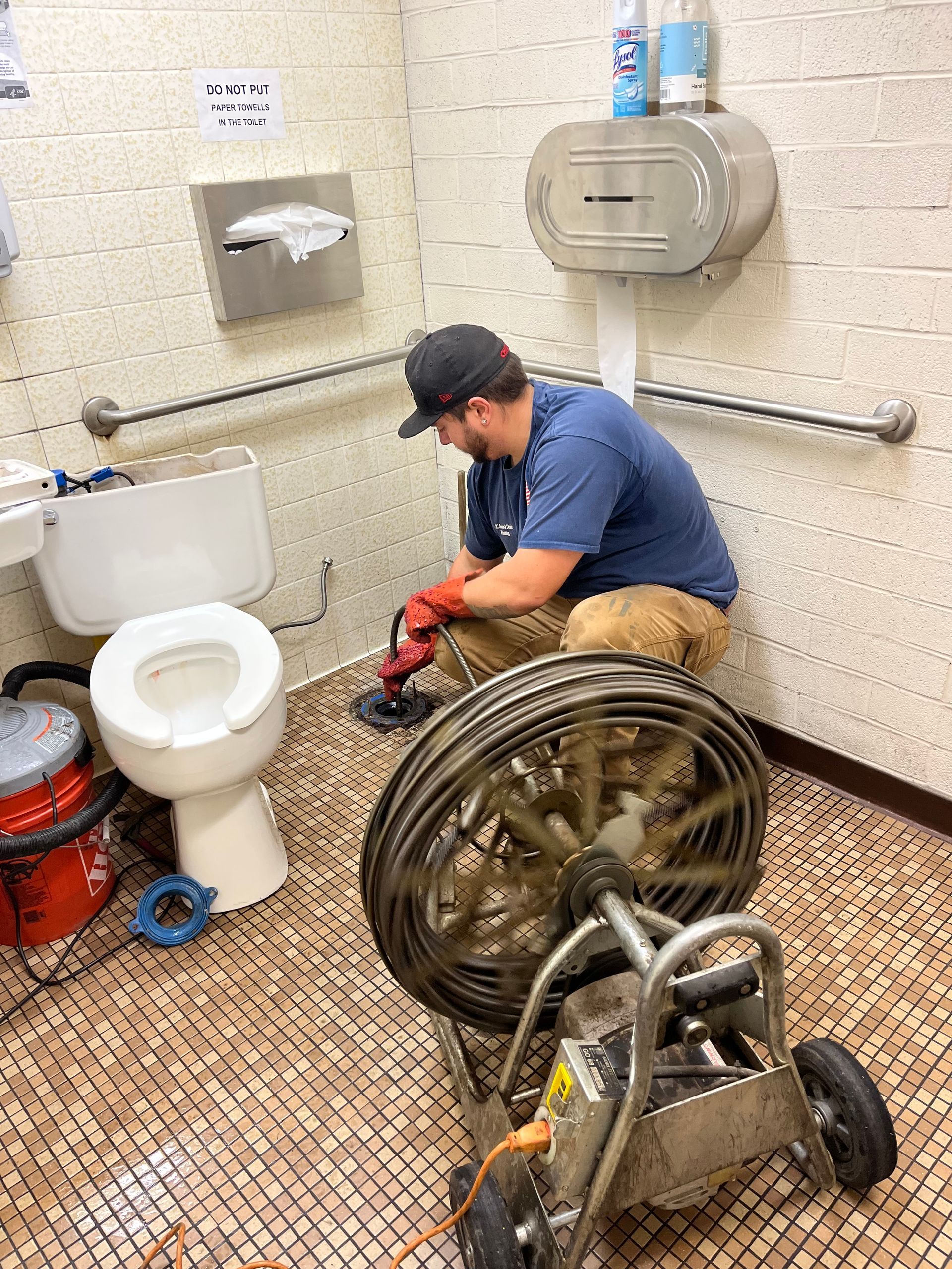 A man is writing on a clipboard next to a water heater.