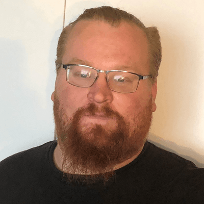 A man with a beard and glasses is wearing a black shirt.