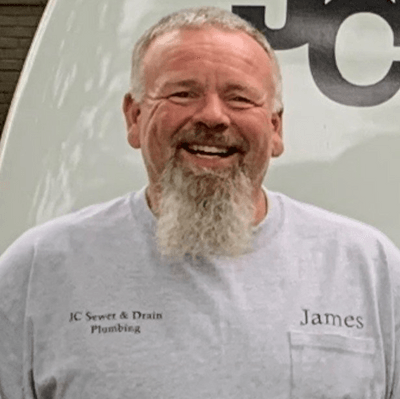 A man with a beard is smiling in front of a van.