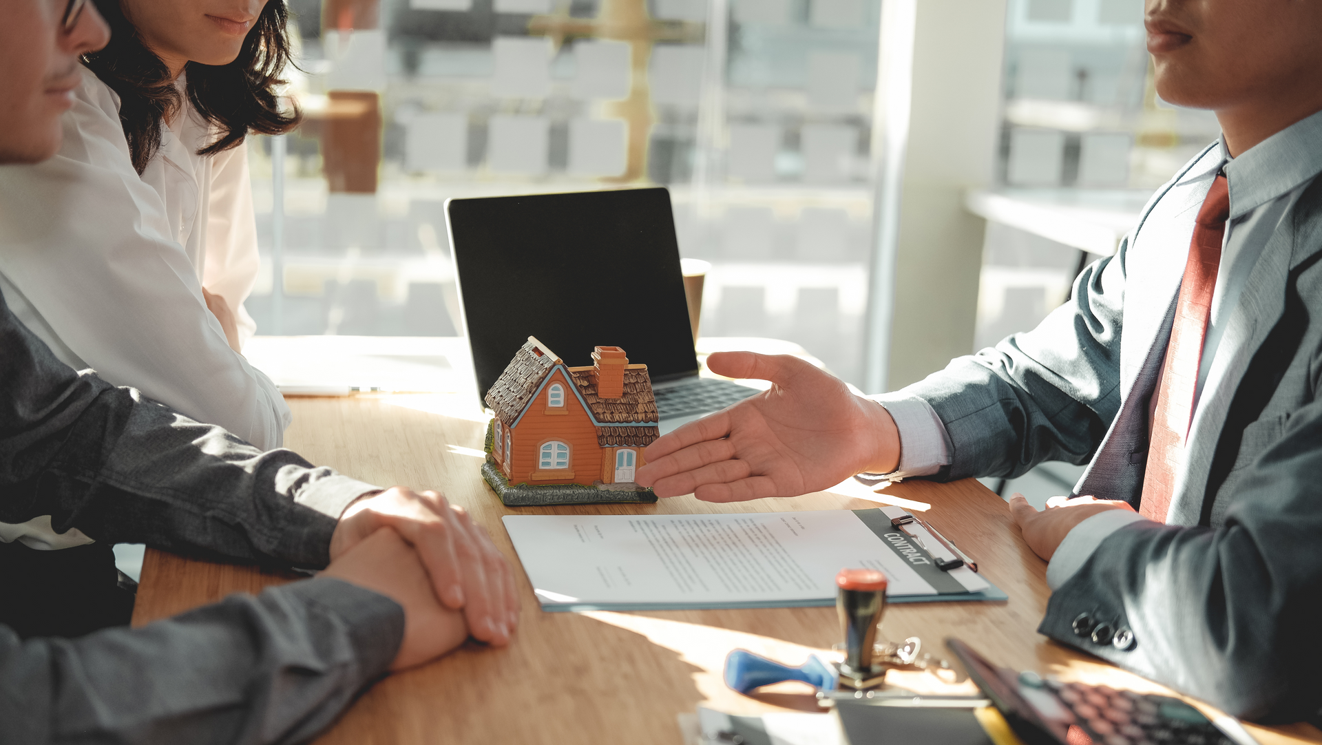 A man and woman are sitting at a table talking to a real estate agent.