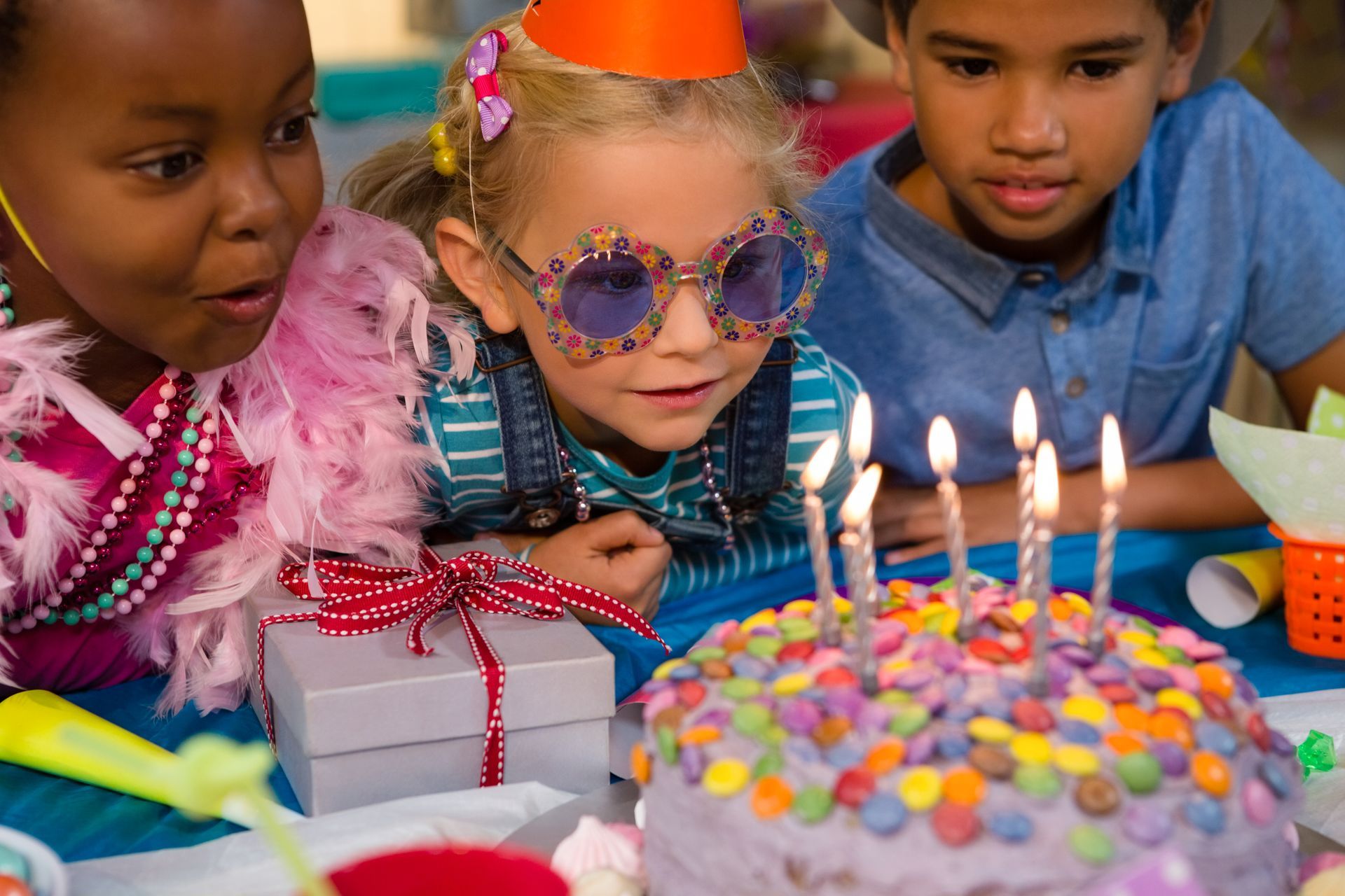 A group of children are blowing out candles on a birthday cake.