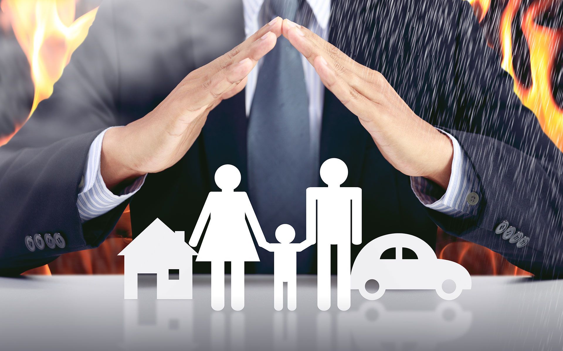 A man in a suit and tie is covering a family , house , and car with his hands.