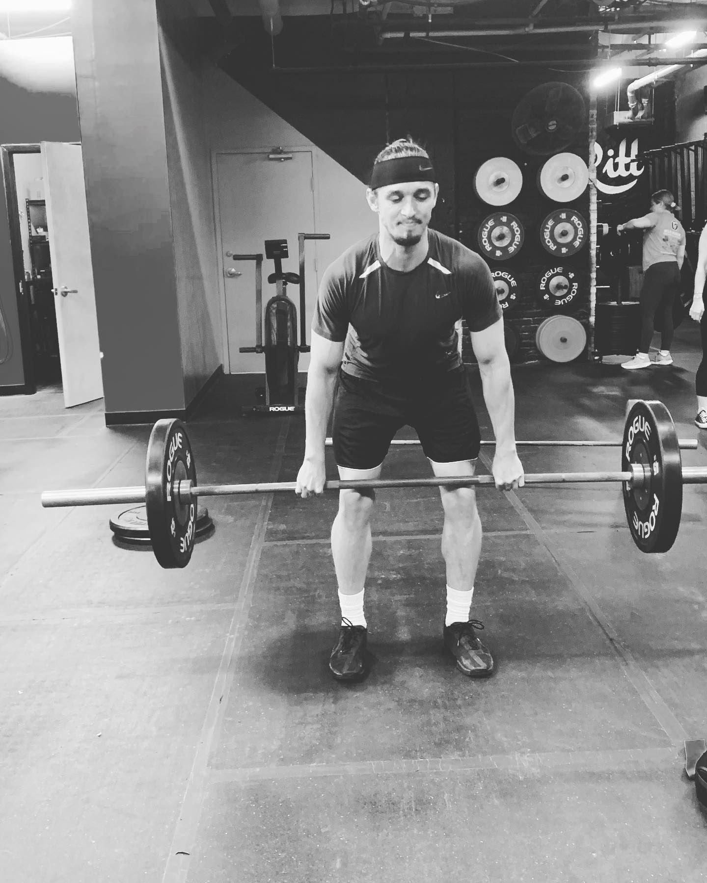 A man is lifting a barbell in a gym.