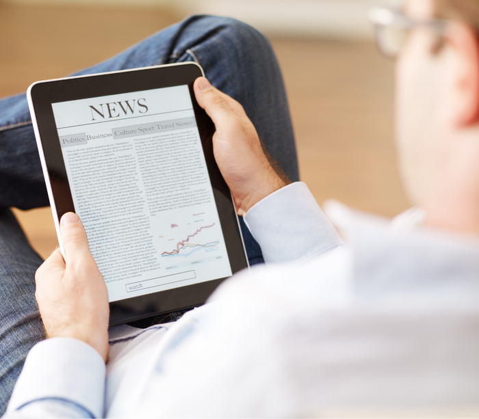 a man is reading a news article on a tablet