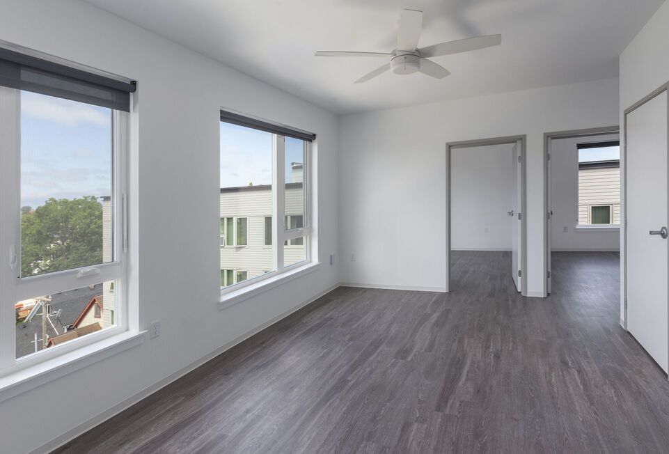 Photo of the living room during a bright day with plenty of natural light coming through the two large windows, plus the room