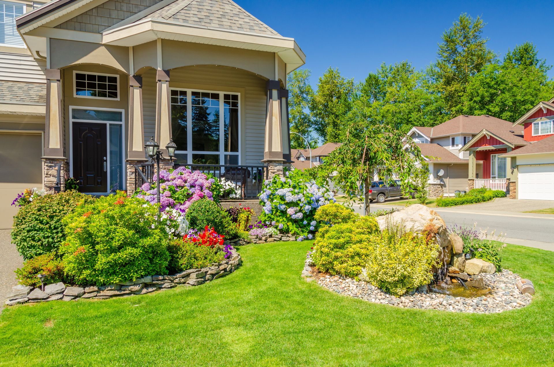 Modern house with landscaped garden, pond, and water fountain in the yard.