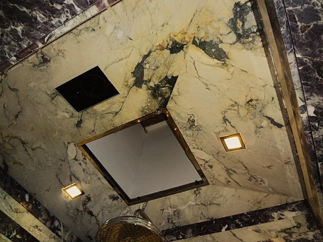 A bathroom with marble walls and a walk in shower.