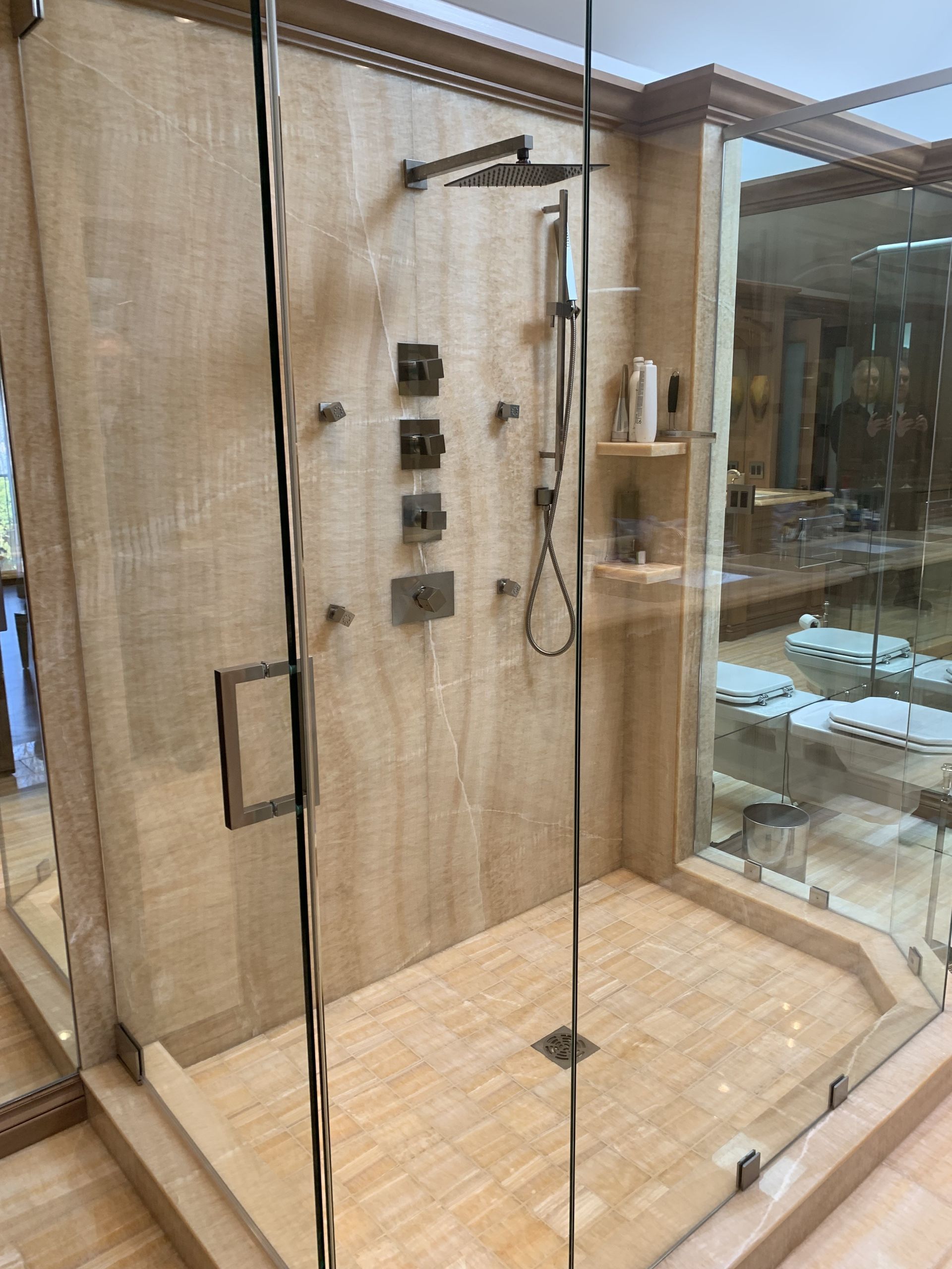 A bathroom with marble walls and floors and a shower.