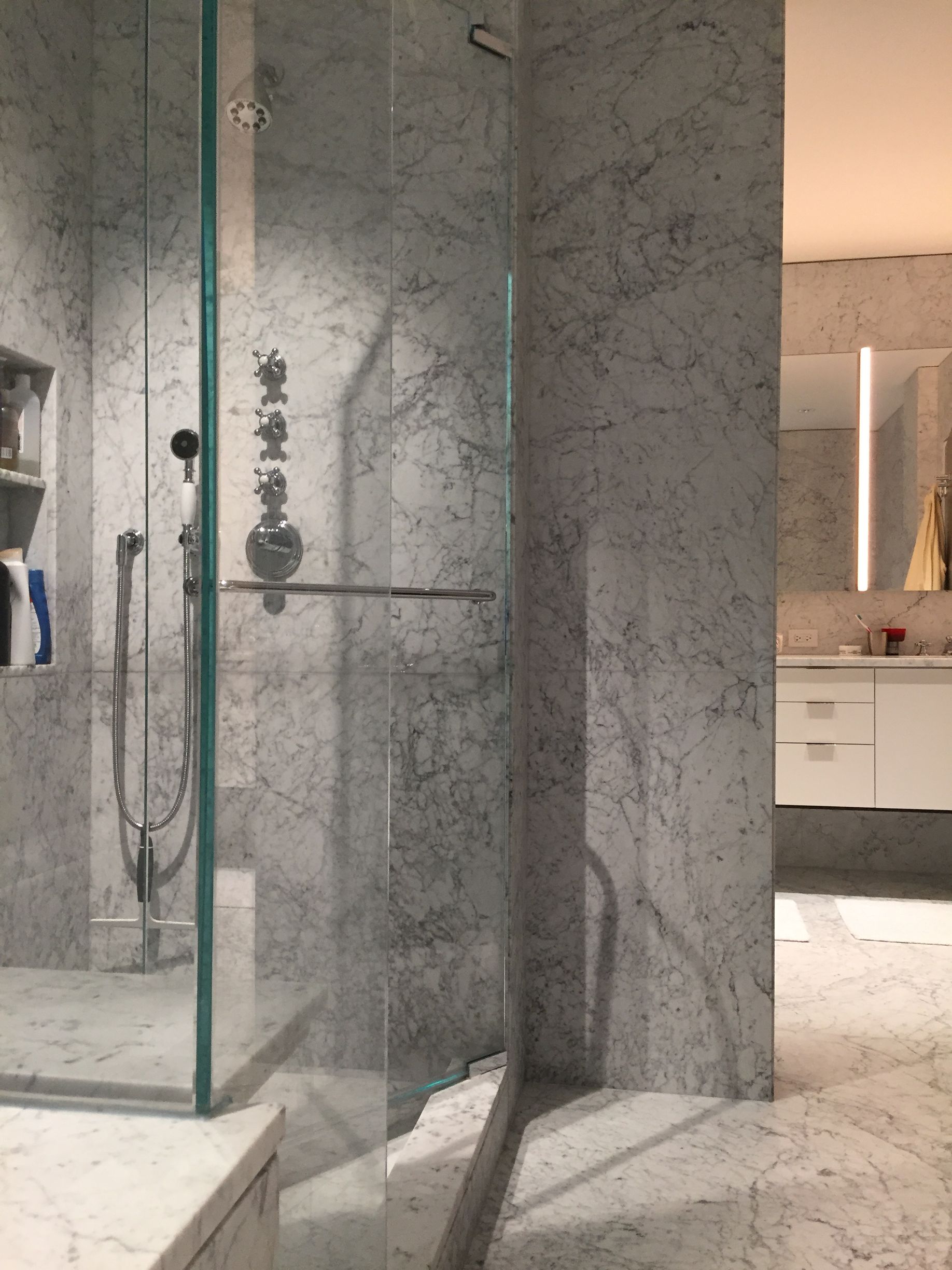 A bathroom with marble walls and a walk in shower.
