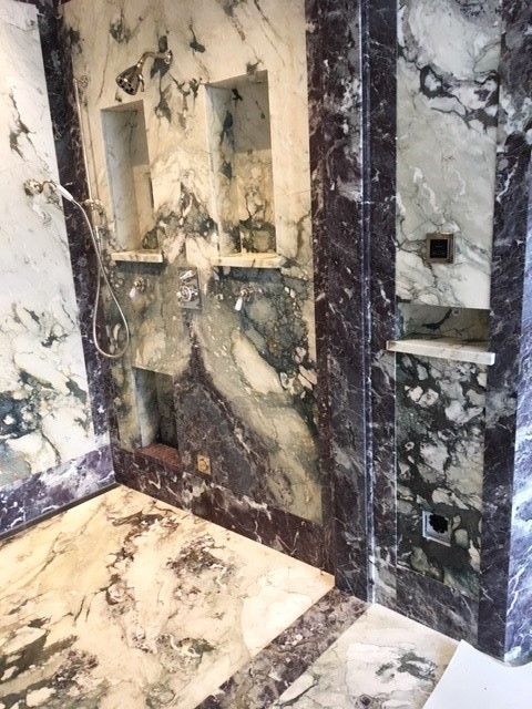 A bathroom with marble walls and a shower head.