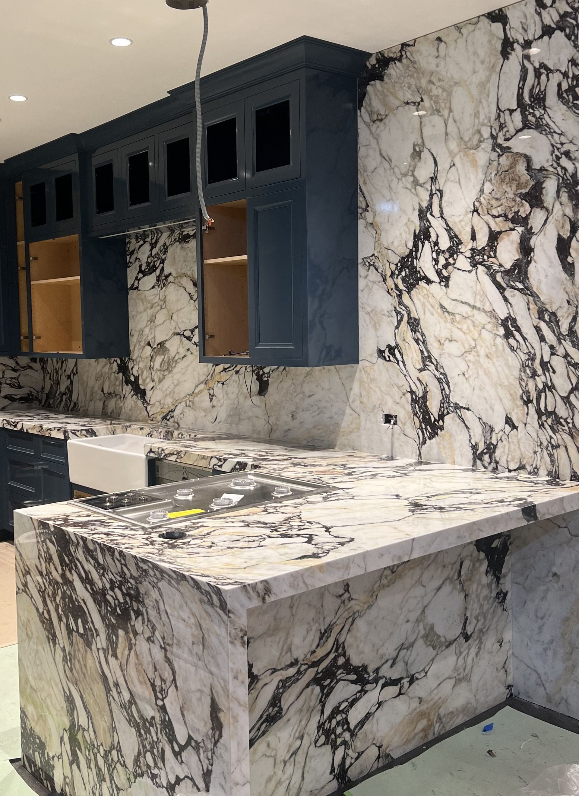 A kitchen with marble counter tops and blue cabinets