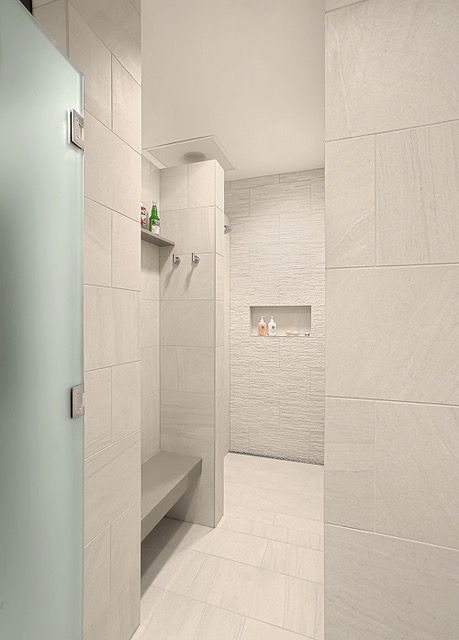 A bathroom with a walk in shower and a bench.