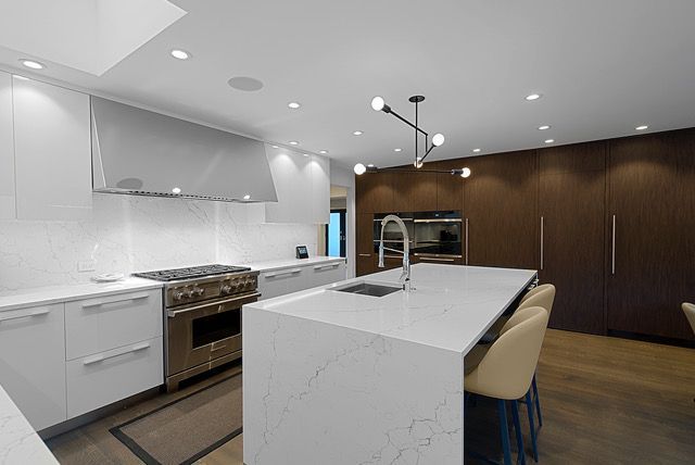 A kitchen with marble counter tops and stainless steel cabinets