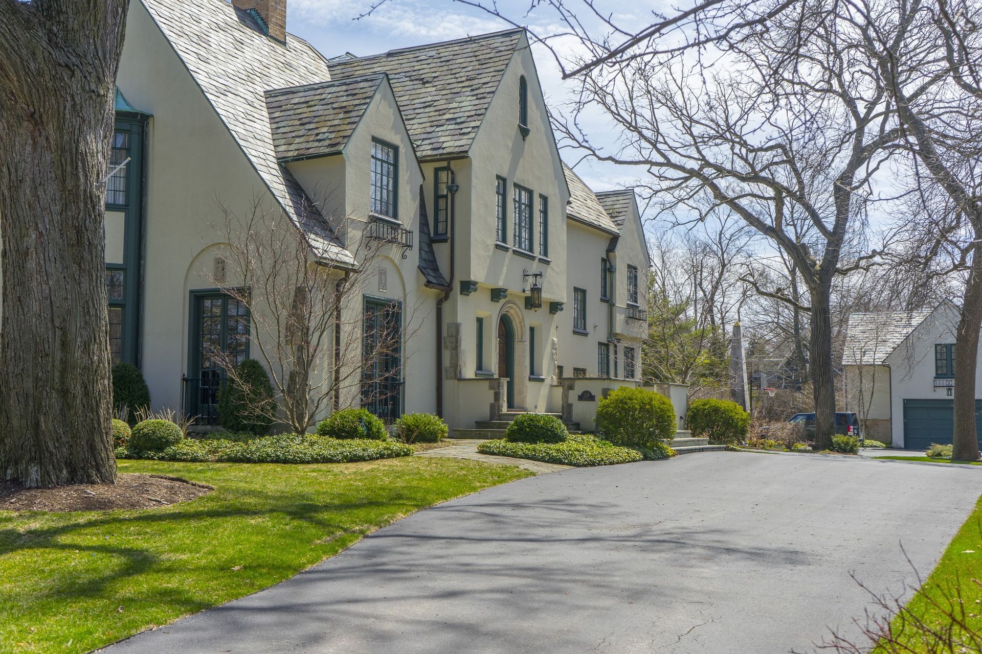 A large stone house with a gravel driveway in front of it.