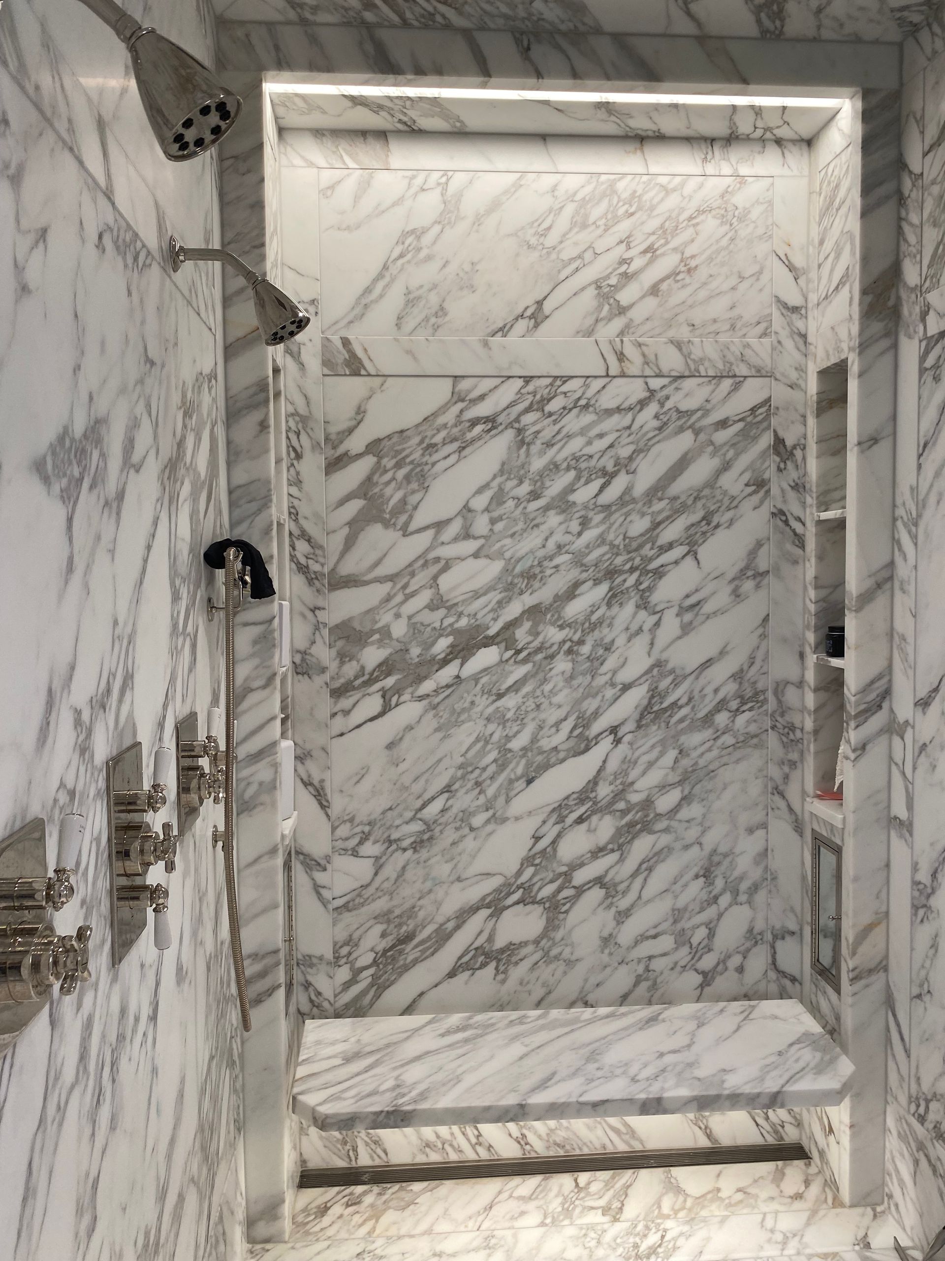 A bathroom with marble walls and a walk in shower.