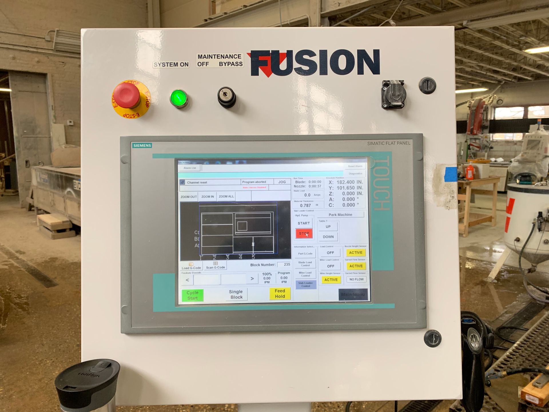 A computer monitor is sitting on top of a control panel in a factory.