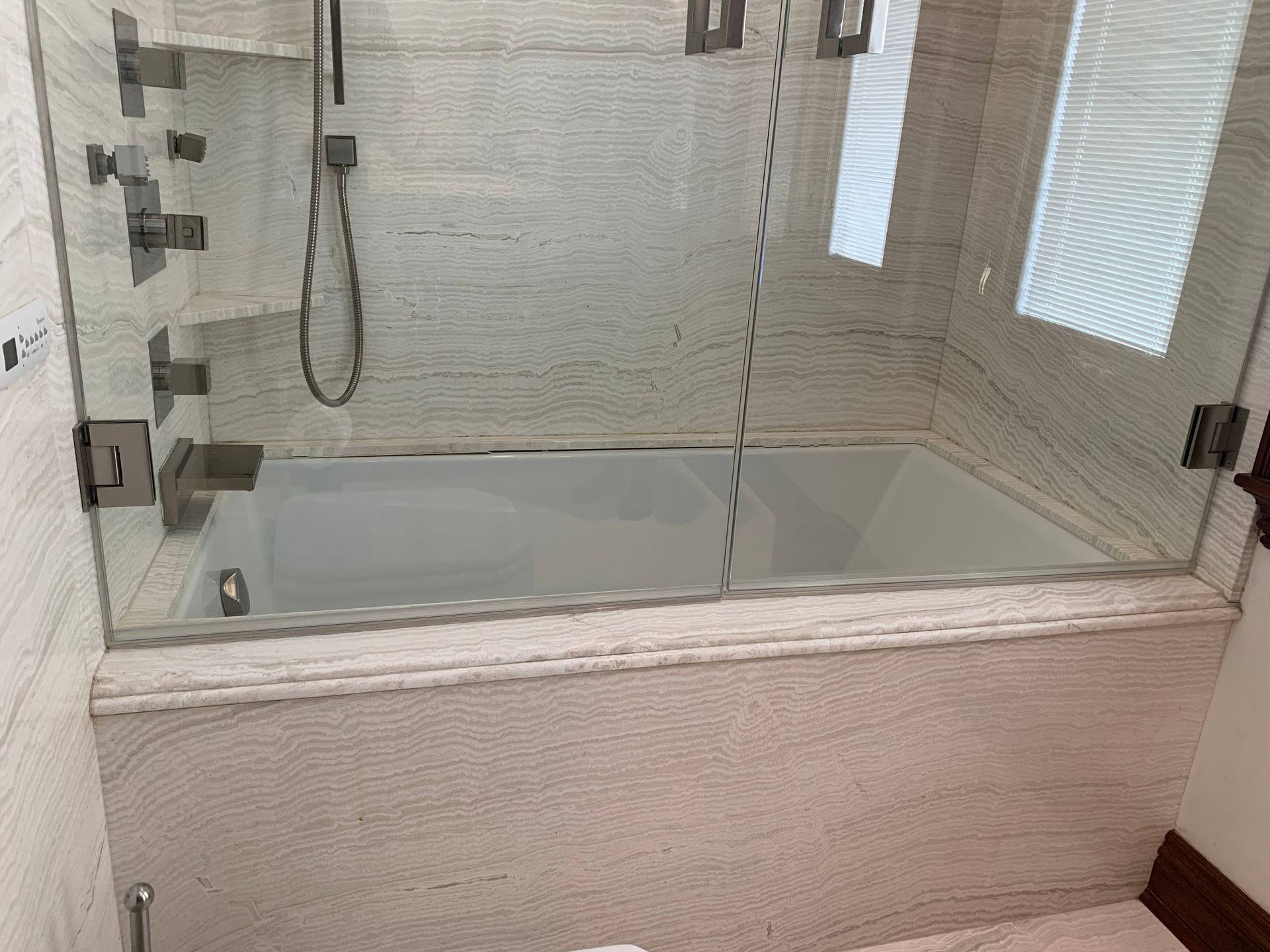 There is a bathtub in the bathroom with a glass shower door.