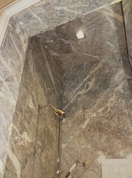A bathroom with marble walls and a shower head.