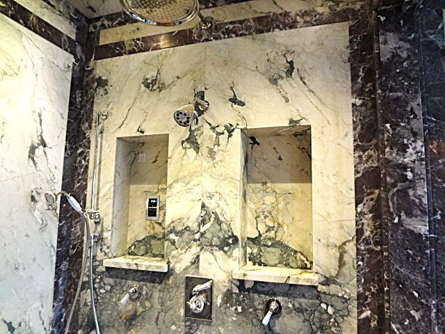 A bathroom with marble walls and a shower head.