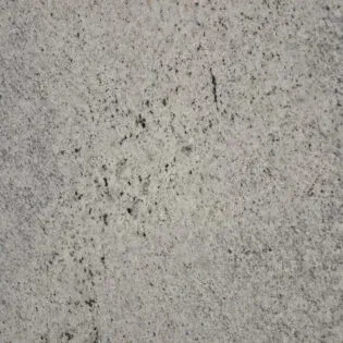 A close up of a white granite counter top with black spots.