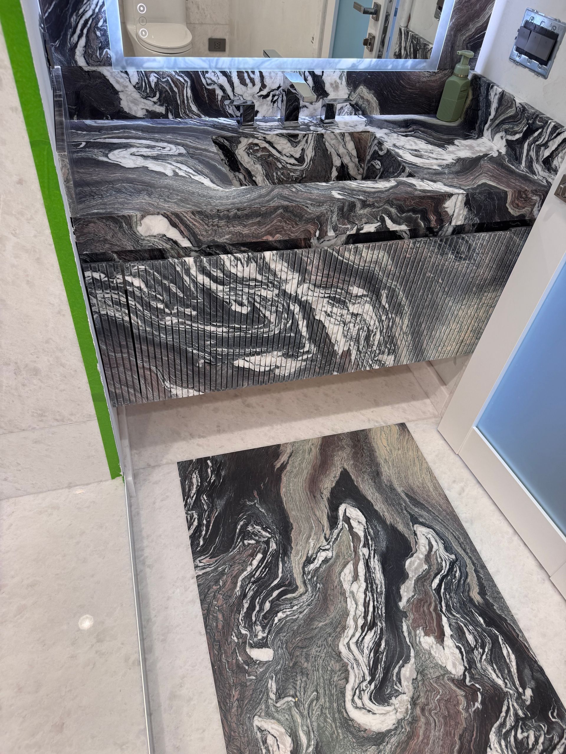 A bathroom with a sink , mirror and walk in shower.