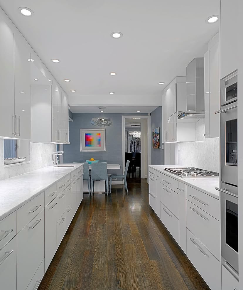 A long kitchen with white cabinets and stainless steel appliances