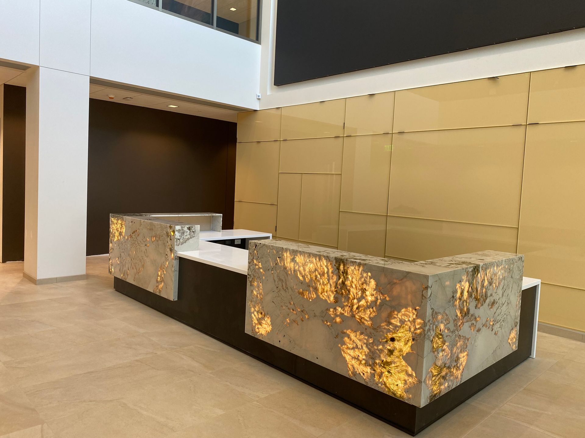 A large lobby with a long reception desk in the middle of it.