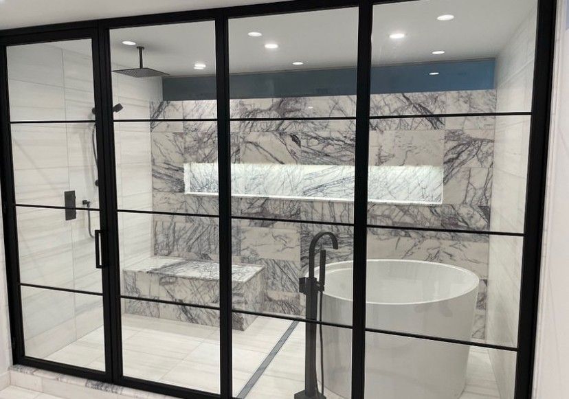 A bathroom with a tub , shower , and sliding glass doors.