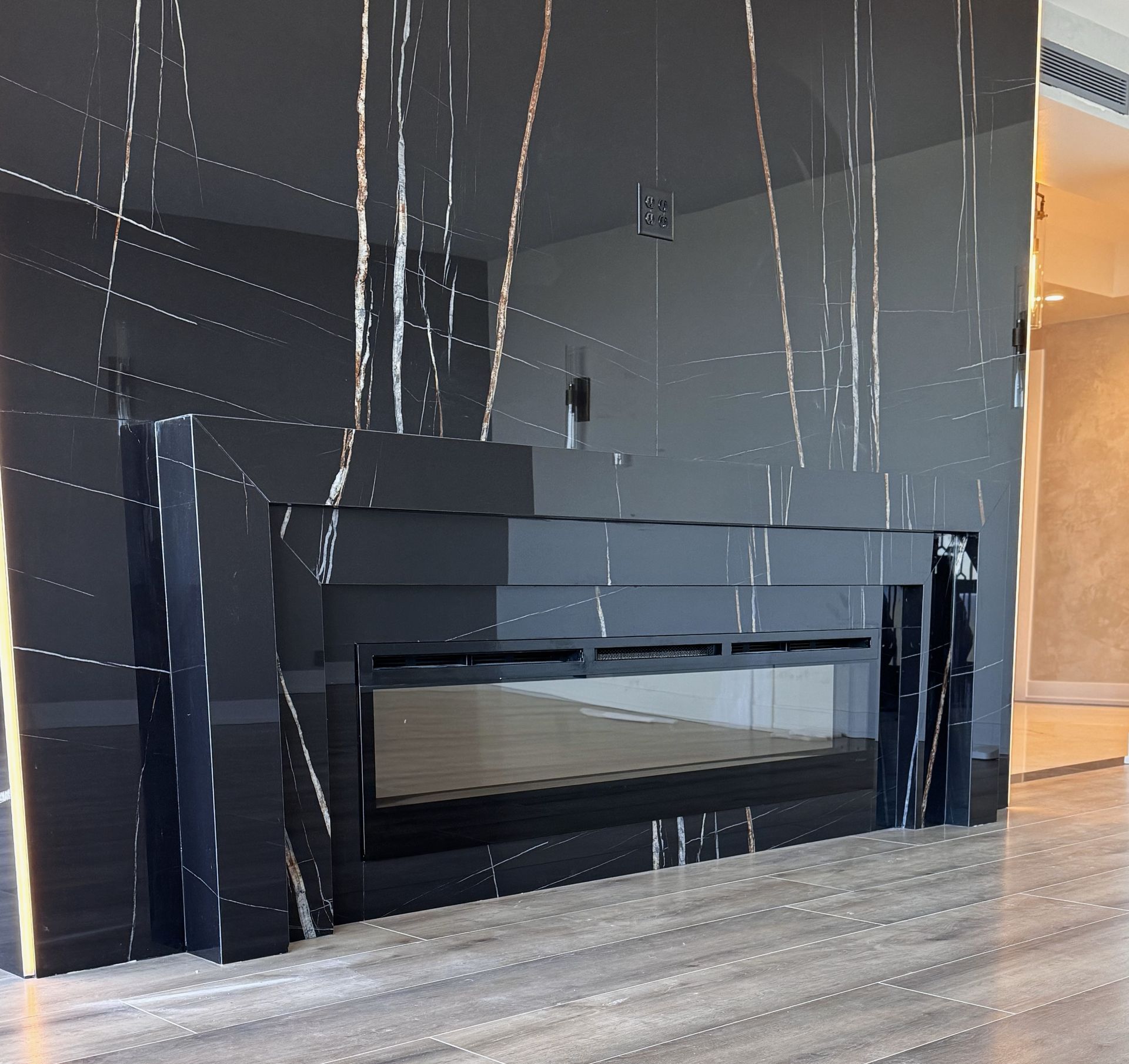 A fireplace with a black marble wall behind it