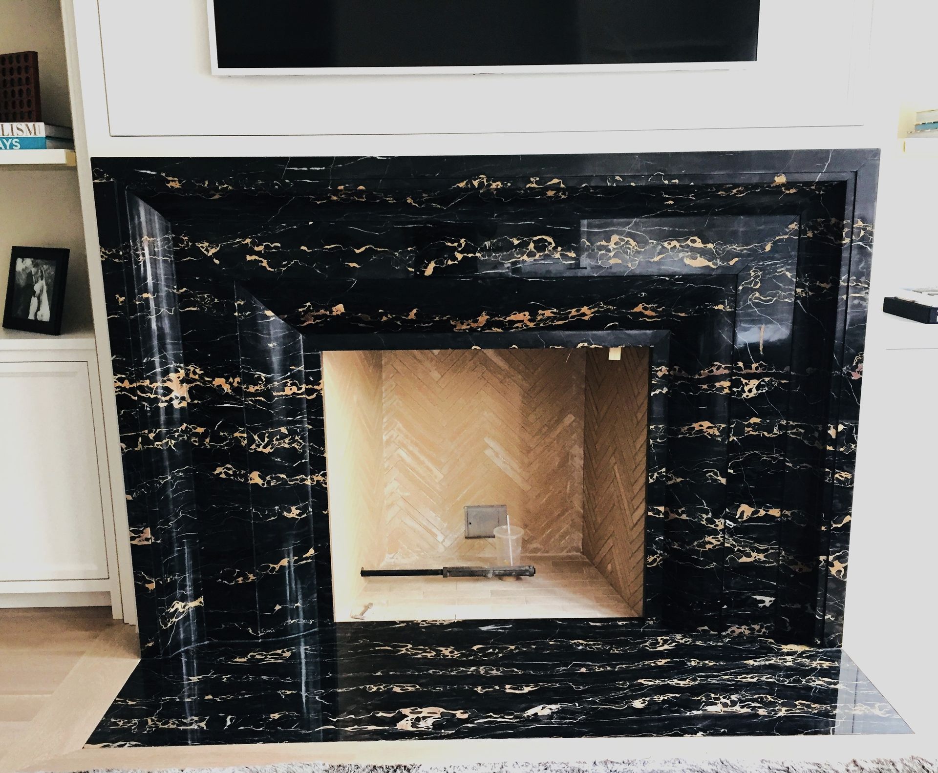 A black and gold fireplace with a flat screen tv above it
