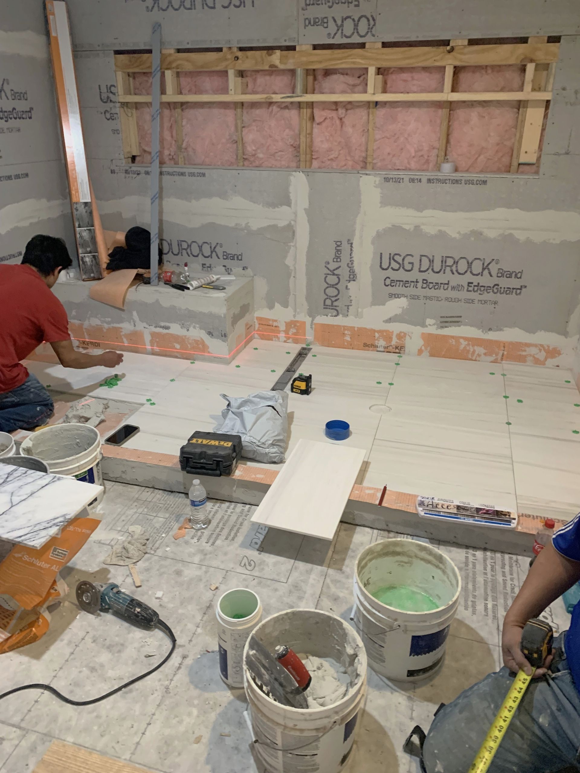 A group of men are working on a bathroom floor.