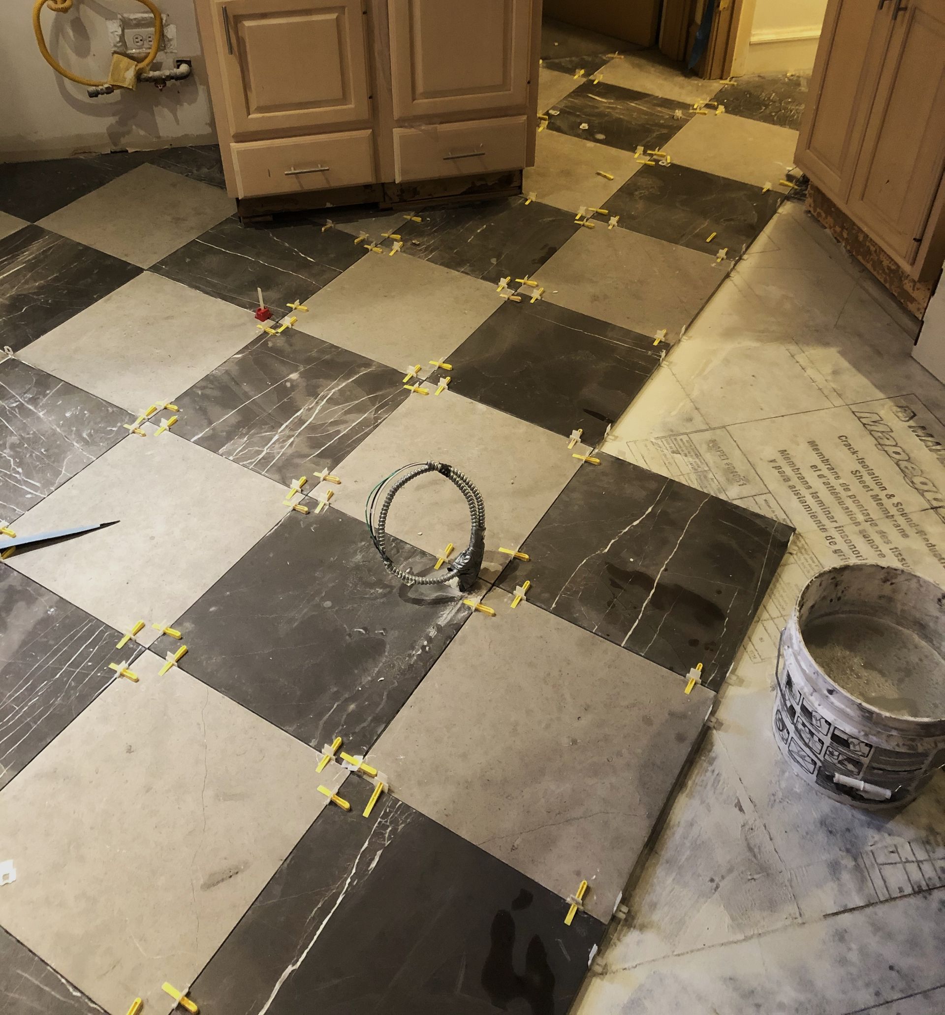A black and white checkered tile floor with a bucket of cement