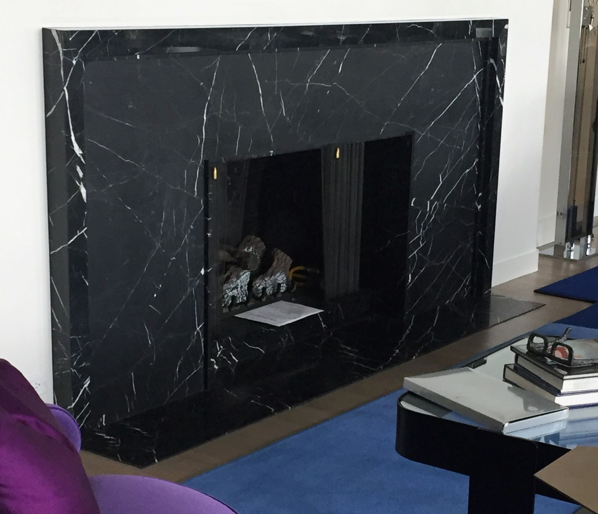 A living room with a fireplace and a purple chair