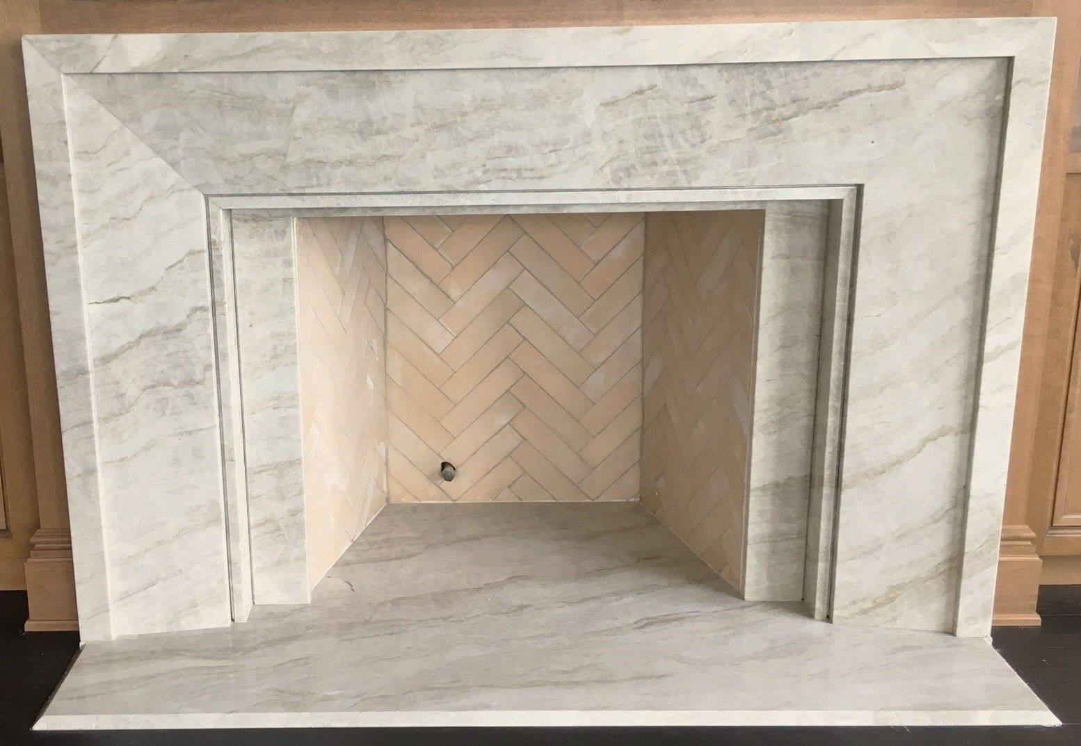 A fireplace with a herringbone pattern on the wall