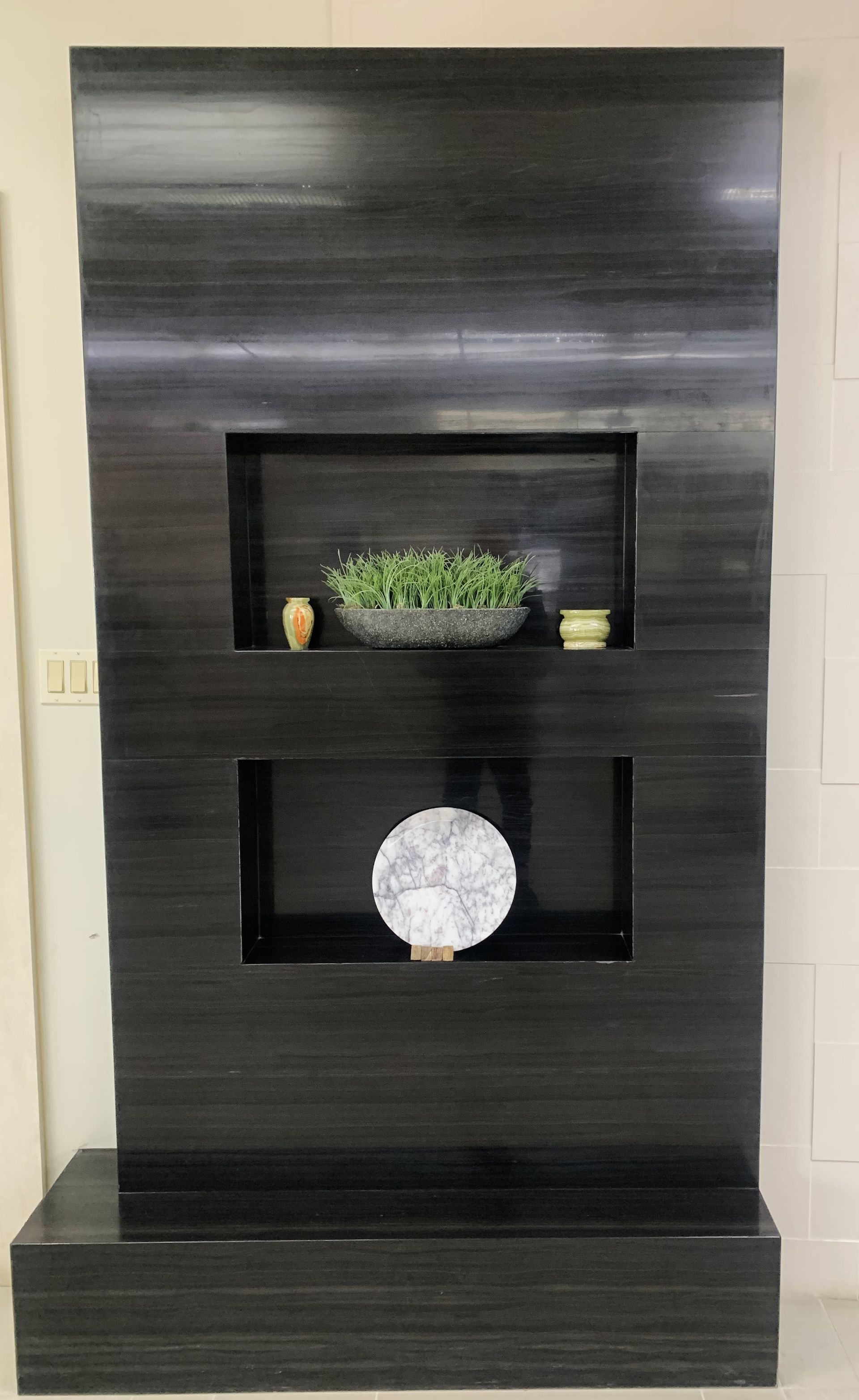 A black wall with three shelves and a plate on it.