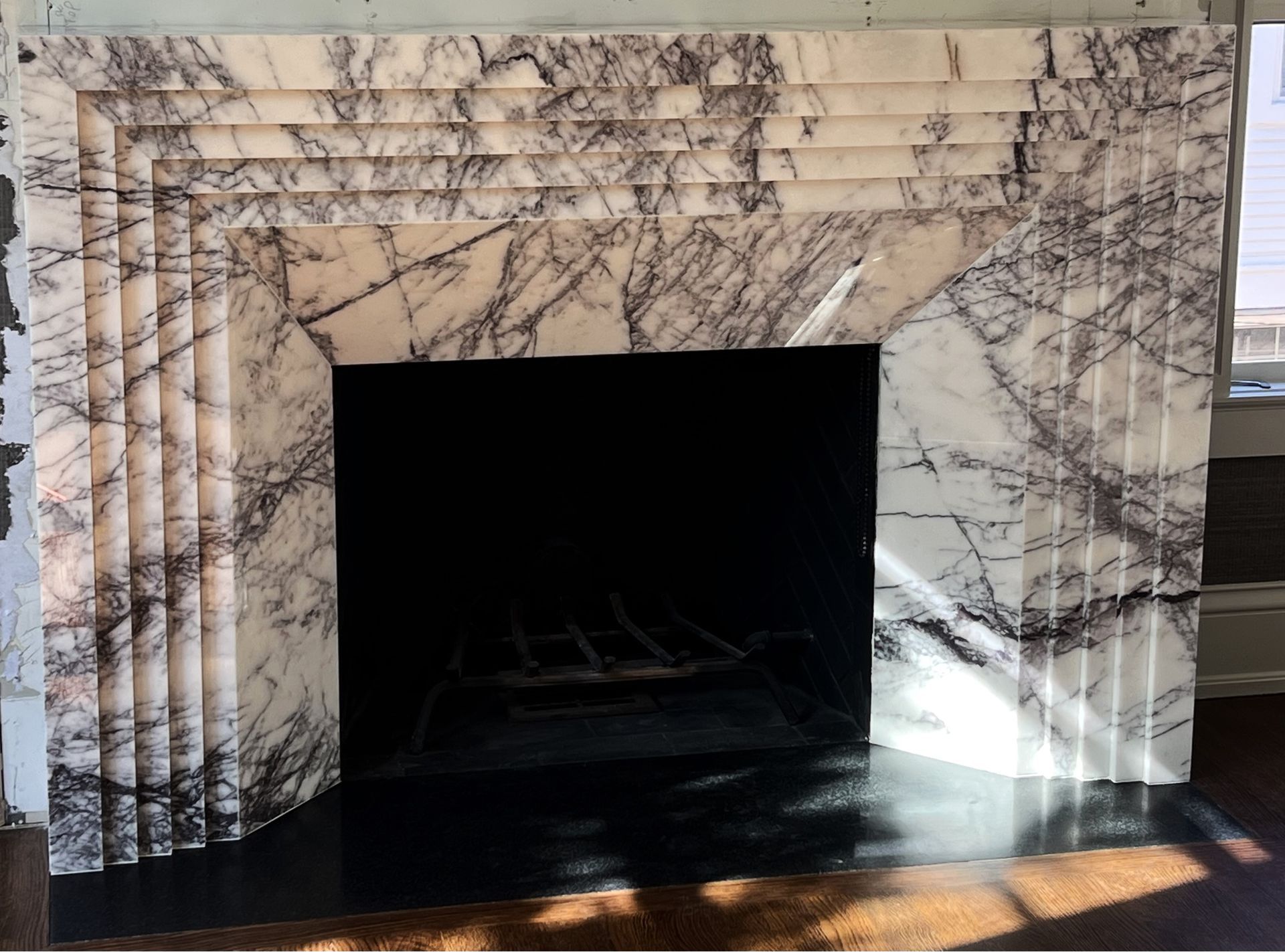 A fireplace with a marble mantle and a black screen