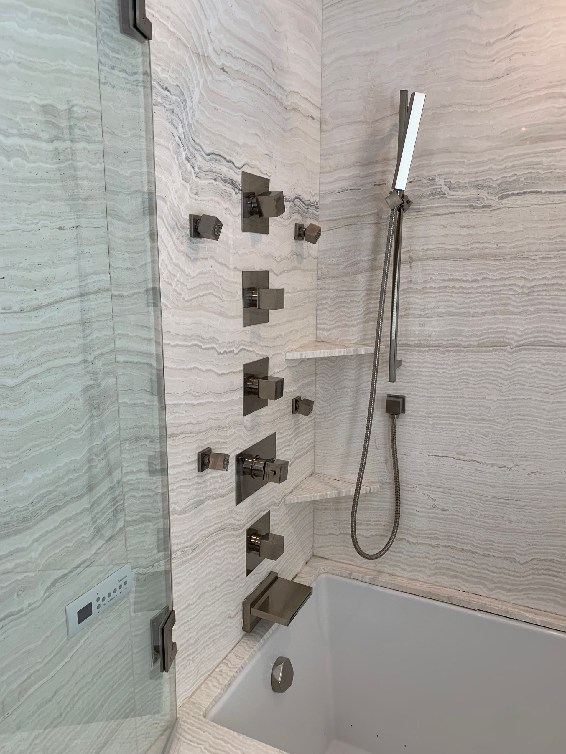 A bathroom with a bathtub , shower , and faucets.