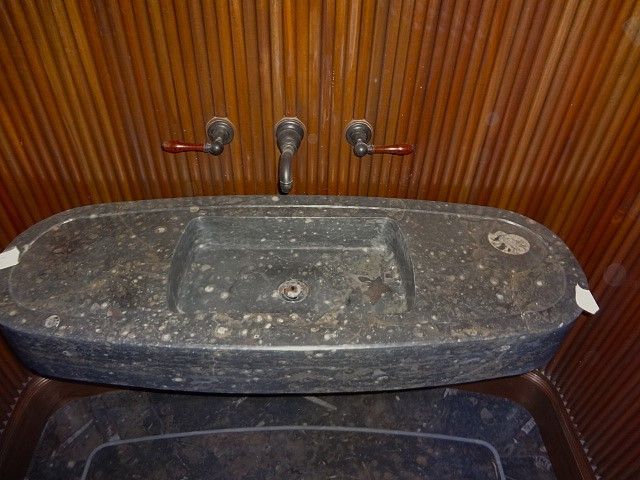 A bathroom sink with a wooden wall behind it