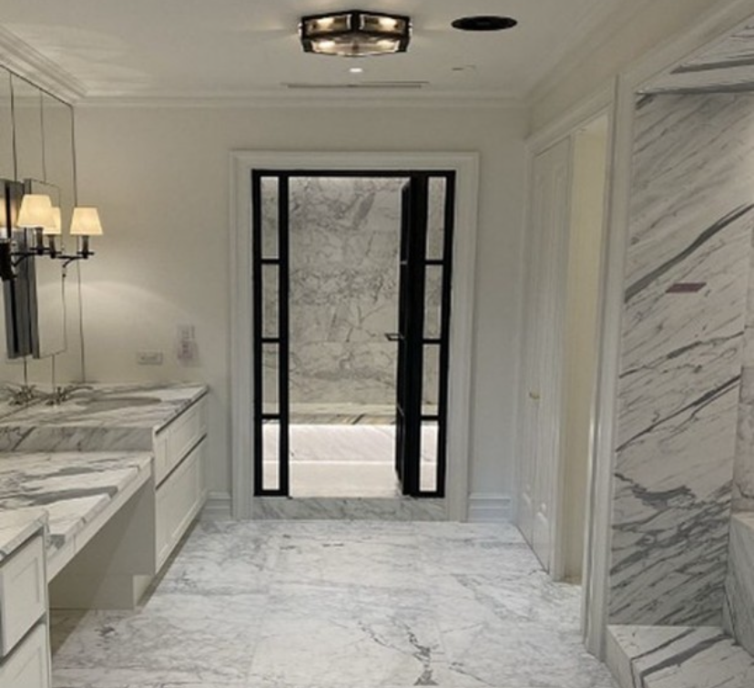A bathroom with marble counter tops and a walk in shower