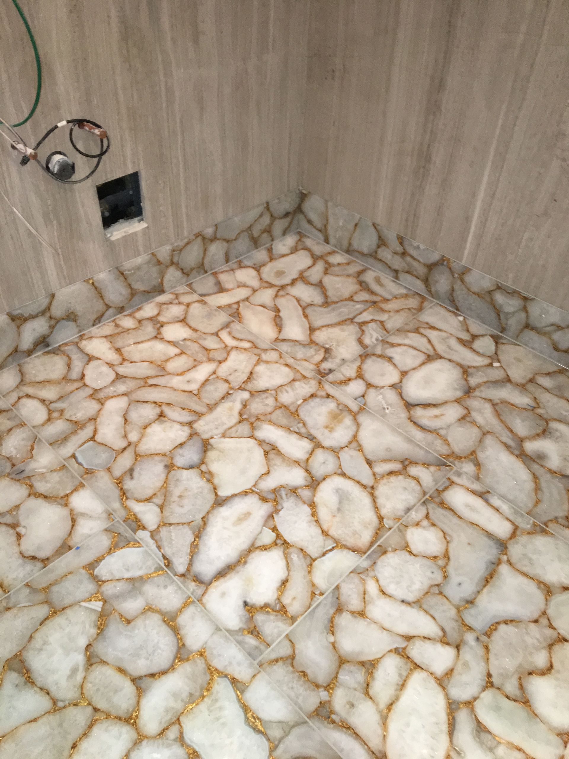 A bathroom with a stone floor and a shower head.