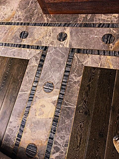 A close up of a wooden floor with a marble border