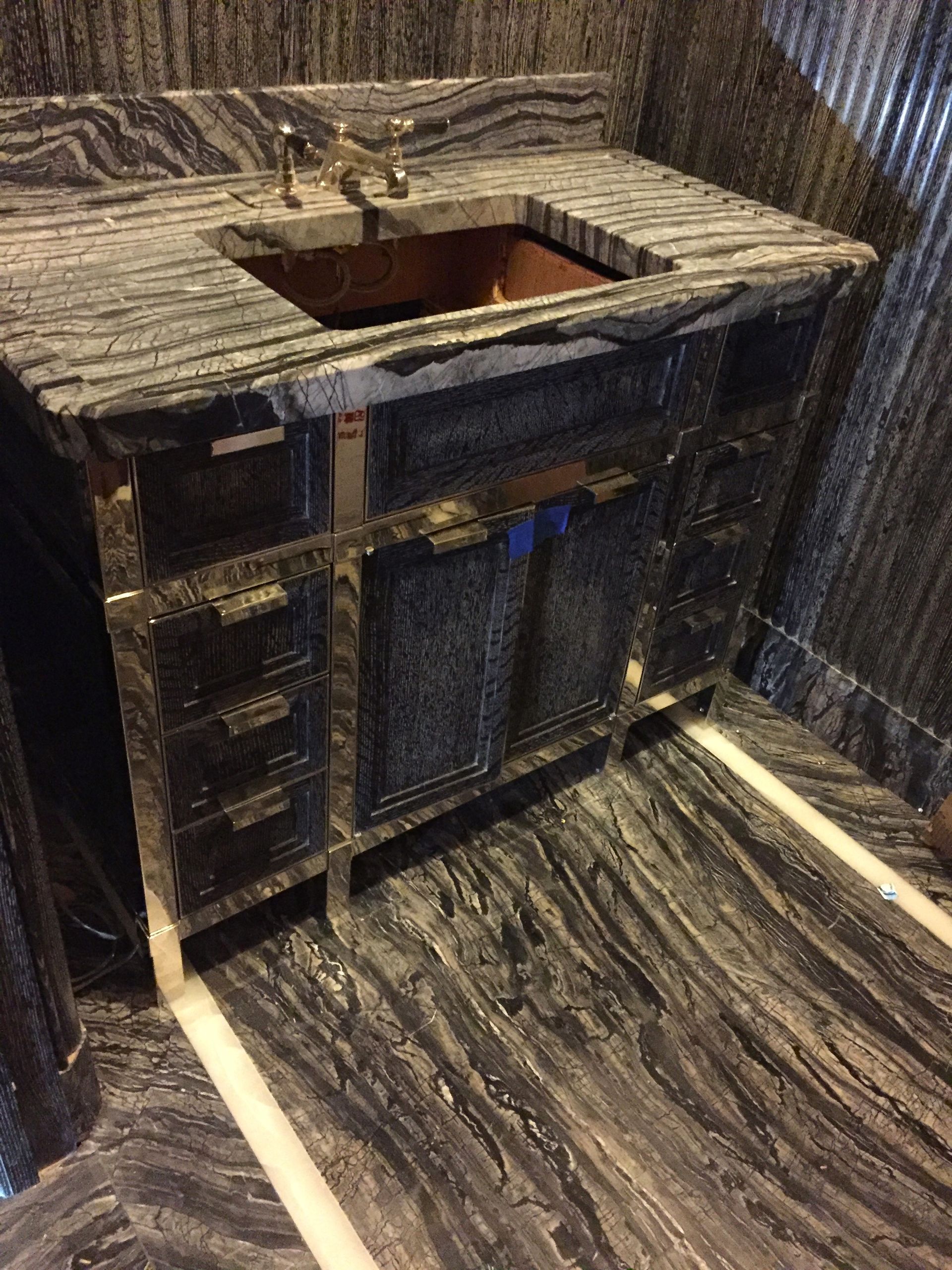 A bathroom vanity with a sink and a marble counter top.